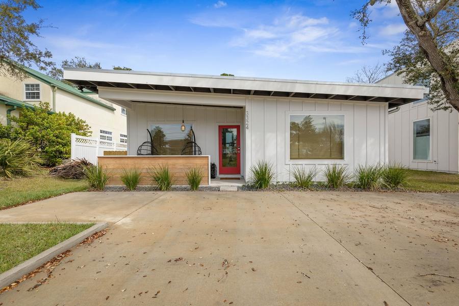 Front of the modern white board-and-batten home with a red door