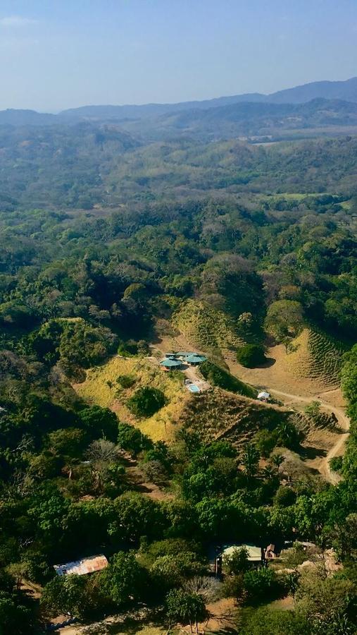 Aerial view of the ranch on a green hilltop surrounded by jungle