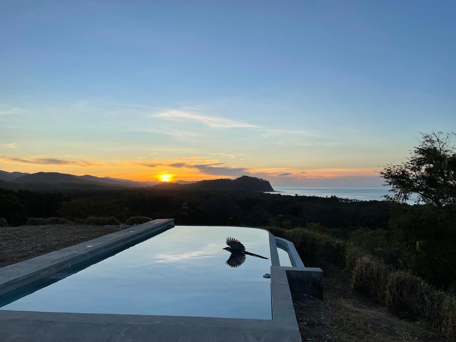 Infinity pool reflecting the sunset over the coast